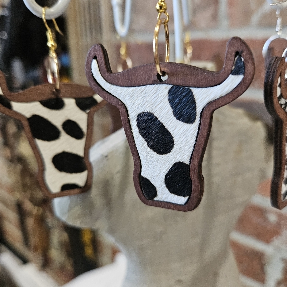Rockin' Hot Originals cow earrings black and white laid in dark wood